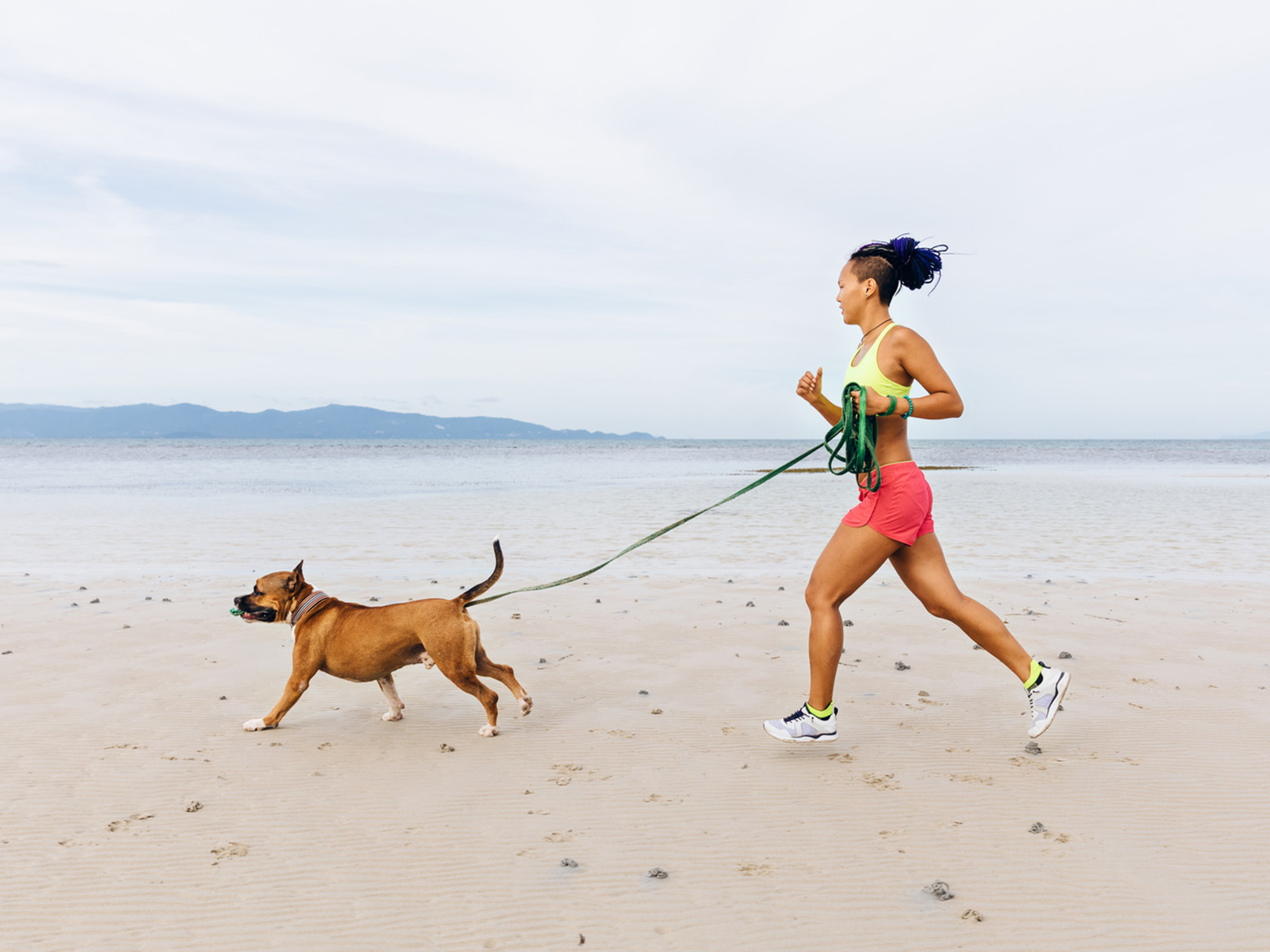 woman running with dog on beach