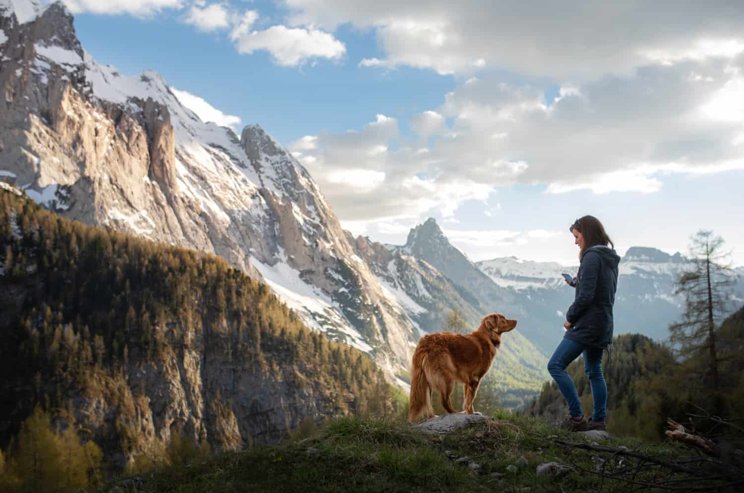 Woman with a dog in the mountains. Autumn mood. Traveling with a pet. Nova Scotia Duck Tolling Retriever