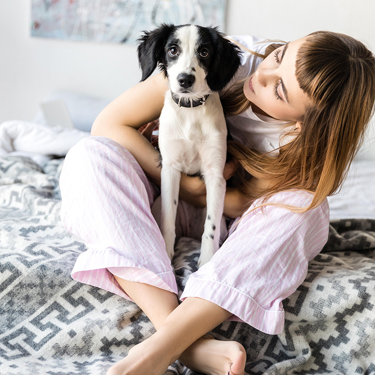 trendy girl with black and white puppy on boho bed