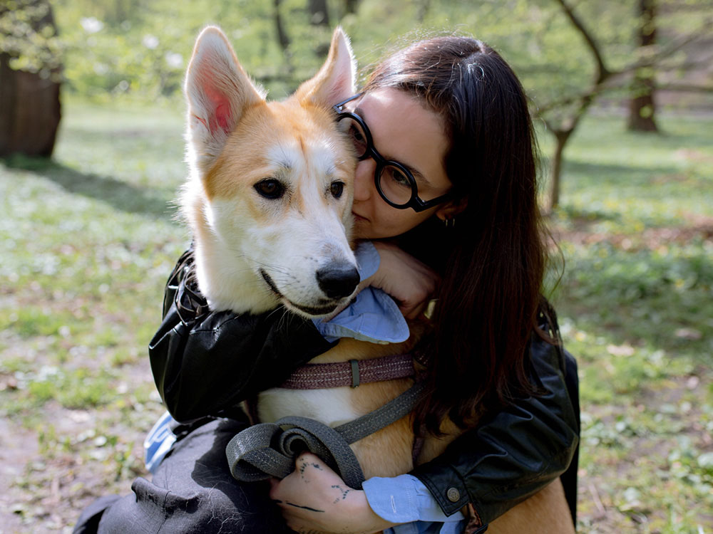 Woman hugs husky mix dog with red and white coat